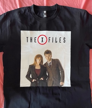 A black T-shirt that says "The X-Files" in the title font of the show over an image of Donna Noble and the Tenth Doctor from Doctor Who posing together.