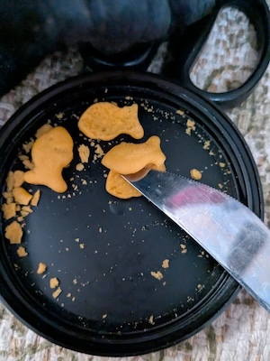 a knife dividing a Goldfish cracker into halves lengthwise 