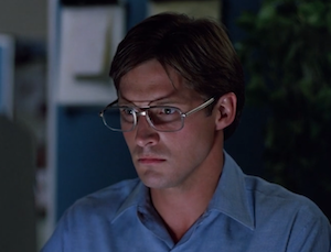 Screenshot of Alan, Tron's programmer, sitting at his computer in the outside world. He looks fascinated and slightly startled