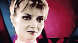 scene from the Deleted Love Scene of the original TRON movie, featuring the computer program Tron and his partner Yori. They look at each other, and the view cuts to the four square circuits on his chest, which she's about to start touching, except that this gif has instead been edited so the top three squares just blink in and out in the pattern of a "loading" ellipsis.